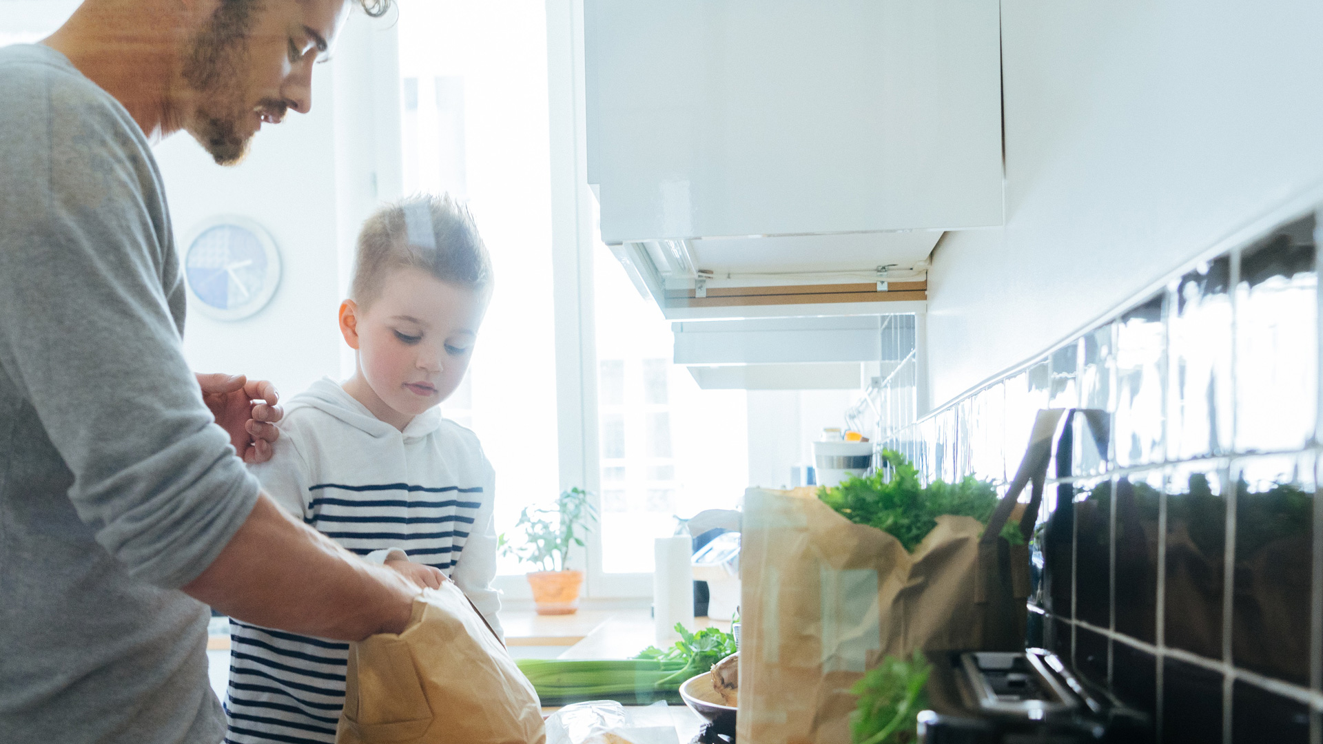 Father and son organizing groceries in kitchen