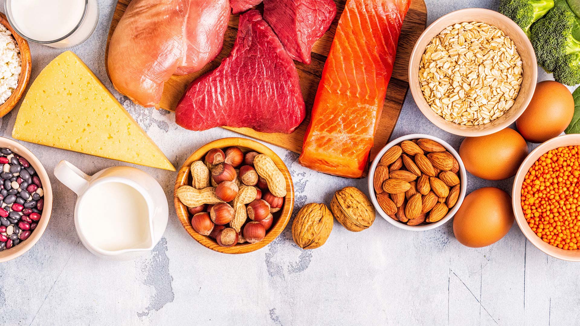 Closeup of raw ingredients eggs, salmon, chicken, seeds, milk, beef, cheese, almonds and beans.